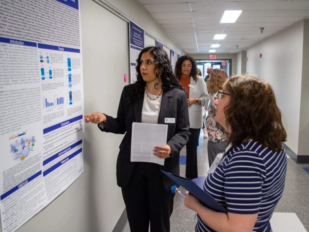 A student presents an internship poster to a faculty member during poster sessions.
