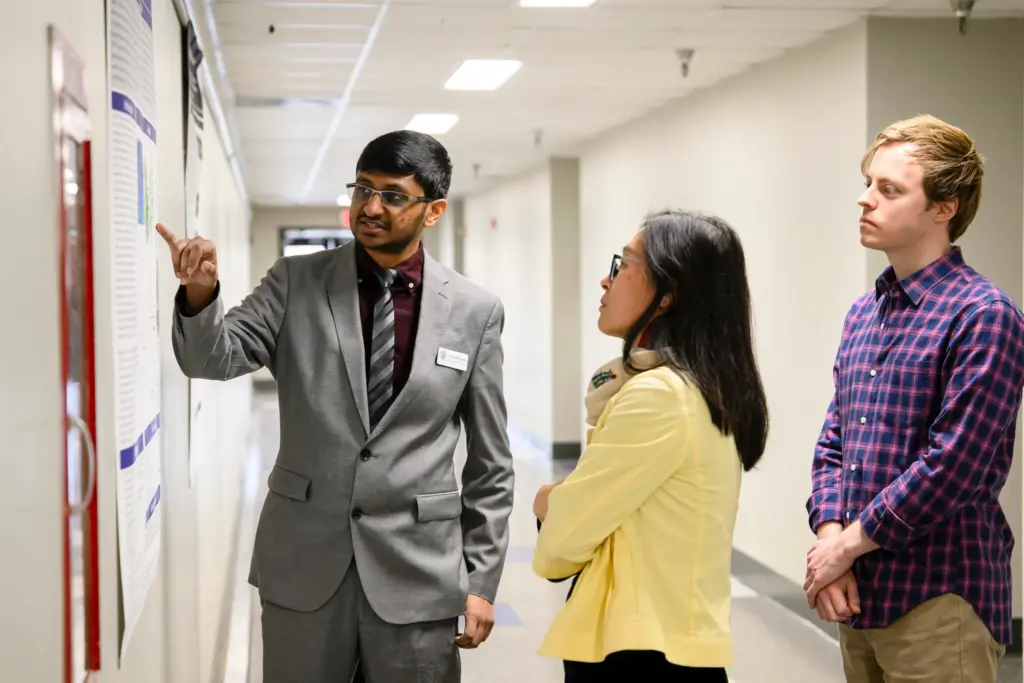 Attendees discuss a poster during the Fall 2023 internship presentations