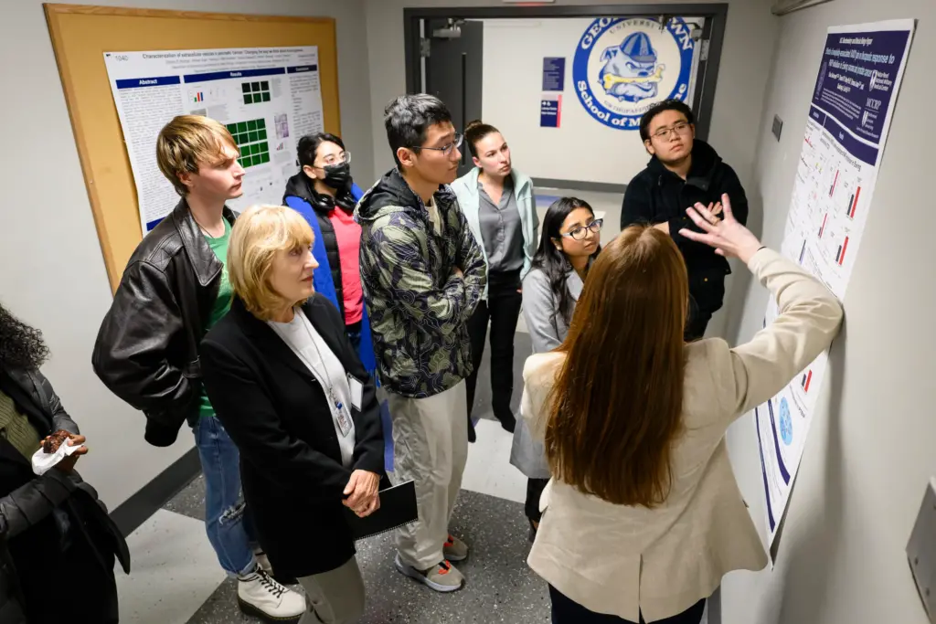 Attendees discuss a poster during the Fall 2023 internship presentations